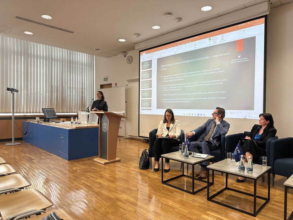 Predavalnica, predavateljica Ana Kerševan pred govorniškim pultom, ob strani sedijo trijedrugi govorci